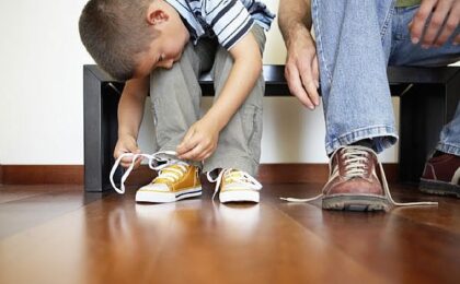 Young boy tying his shoes