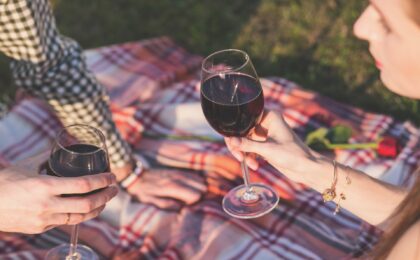 man and woman sharing wine on a blanket