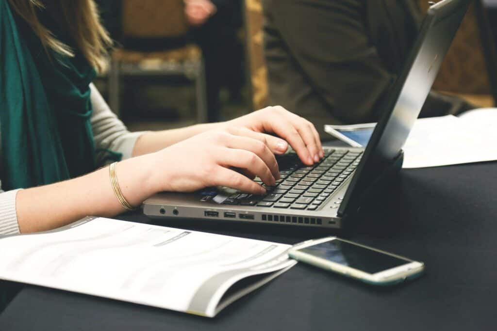 girl at laptop with phone on desk home business