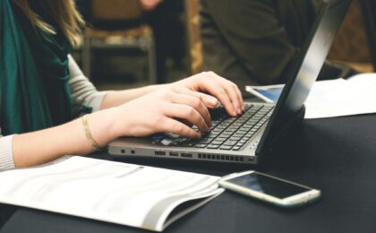 girl at laptop with phone on desk home business