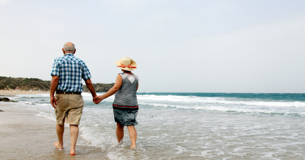 Retired couple walking along beach depicting how life might be if you retire with MLM over 50