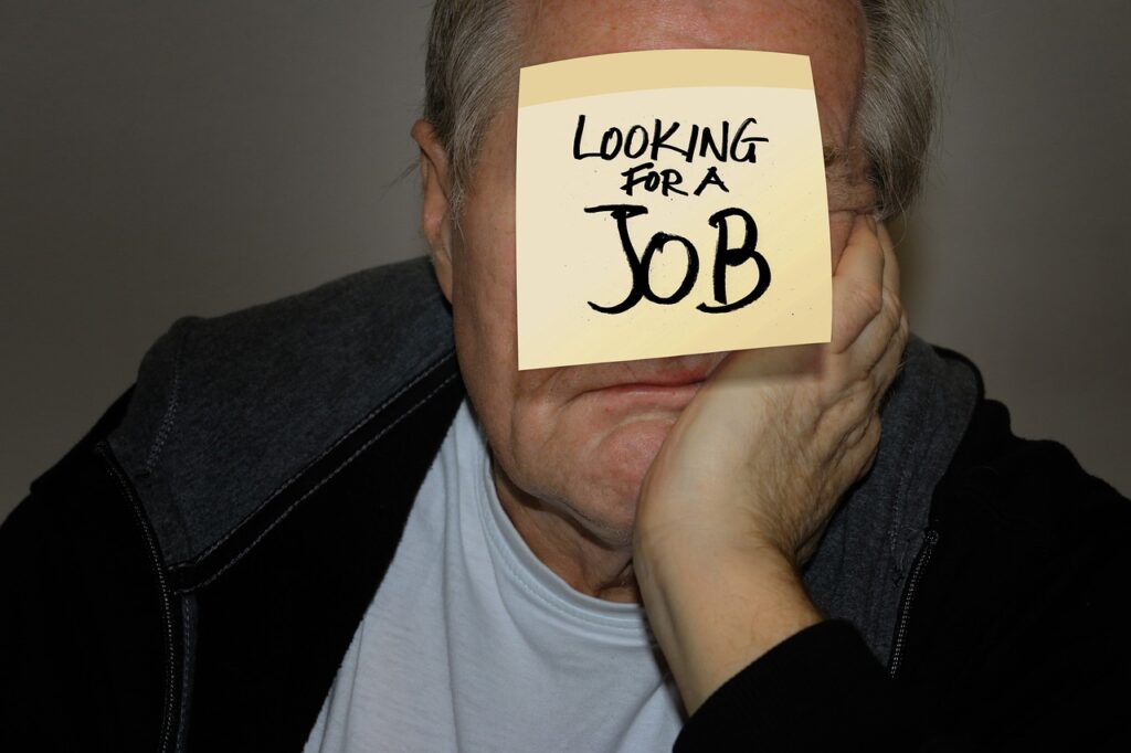 Middle-aged man with sticker on forehead stating "Looking for a job"